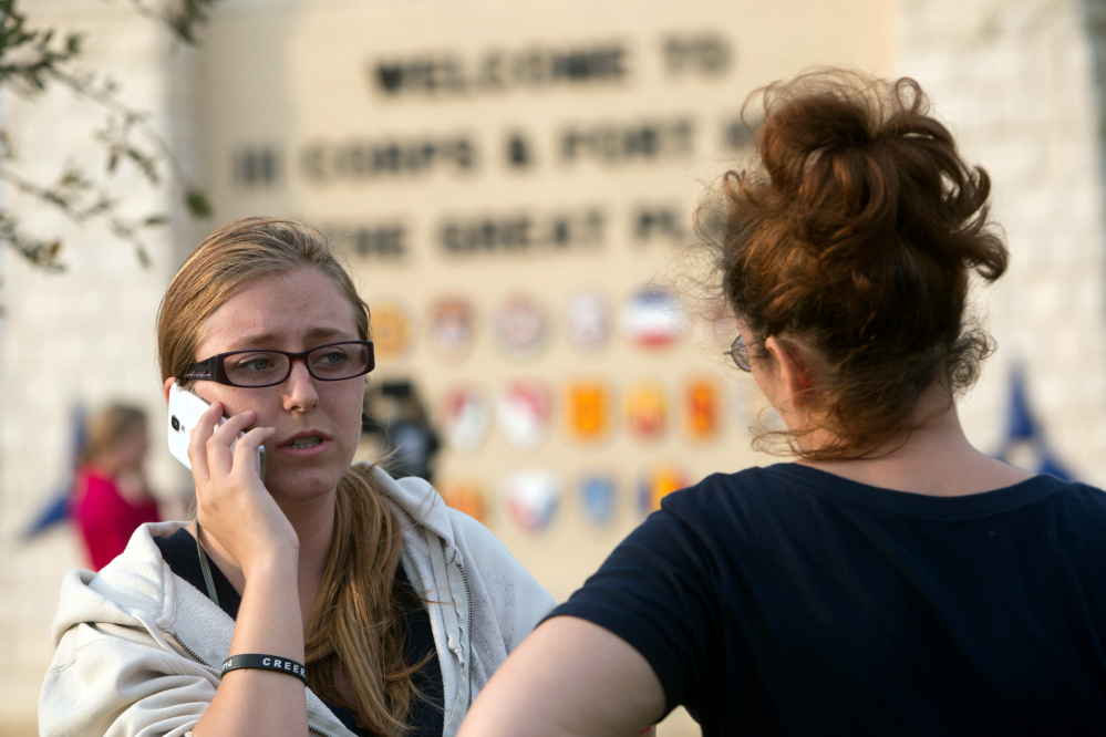 Krystina Cassidy, left, and Dianna Simpson attempt to make contact with their husbands who are stationed inside Fort Hood while standing outside of the Bernie Beck Gate on Wednesday, April 2, 2014, in Fort Hood, Texas. At least one person was killed and 14 injured in the shooting, and officials at the base said the shooter is believed to be dead.