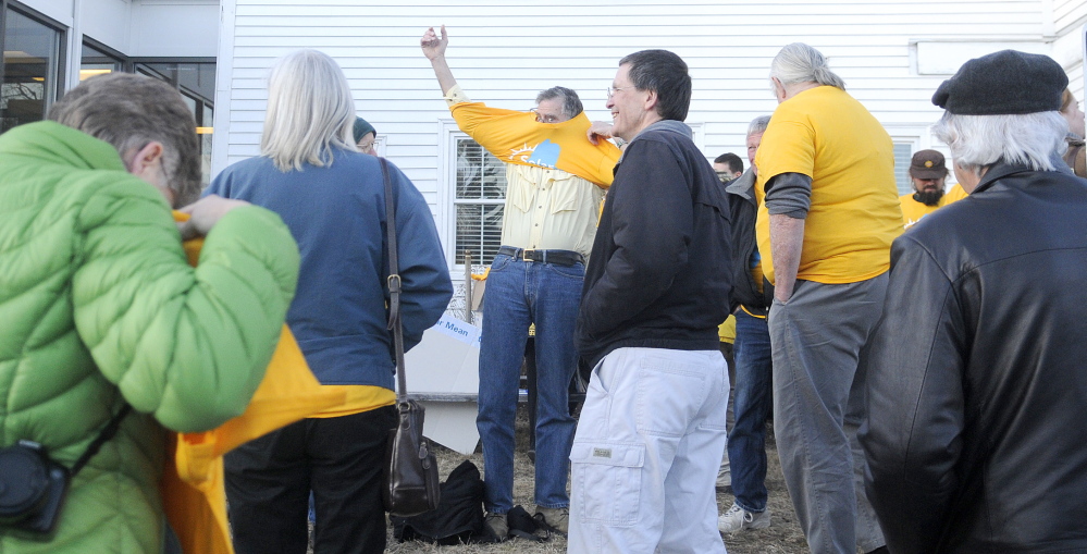 Staff photo by Andy Molloy FIGHT THE POWER: Supporters of solar energy put on yellow t-shirts Wednesday outside of the Public Utility Commissions offices in Hallowell before a hearing for Central Maine Power’s request for a rate increase. About two dozen people attended the gathering.