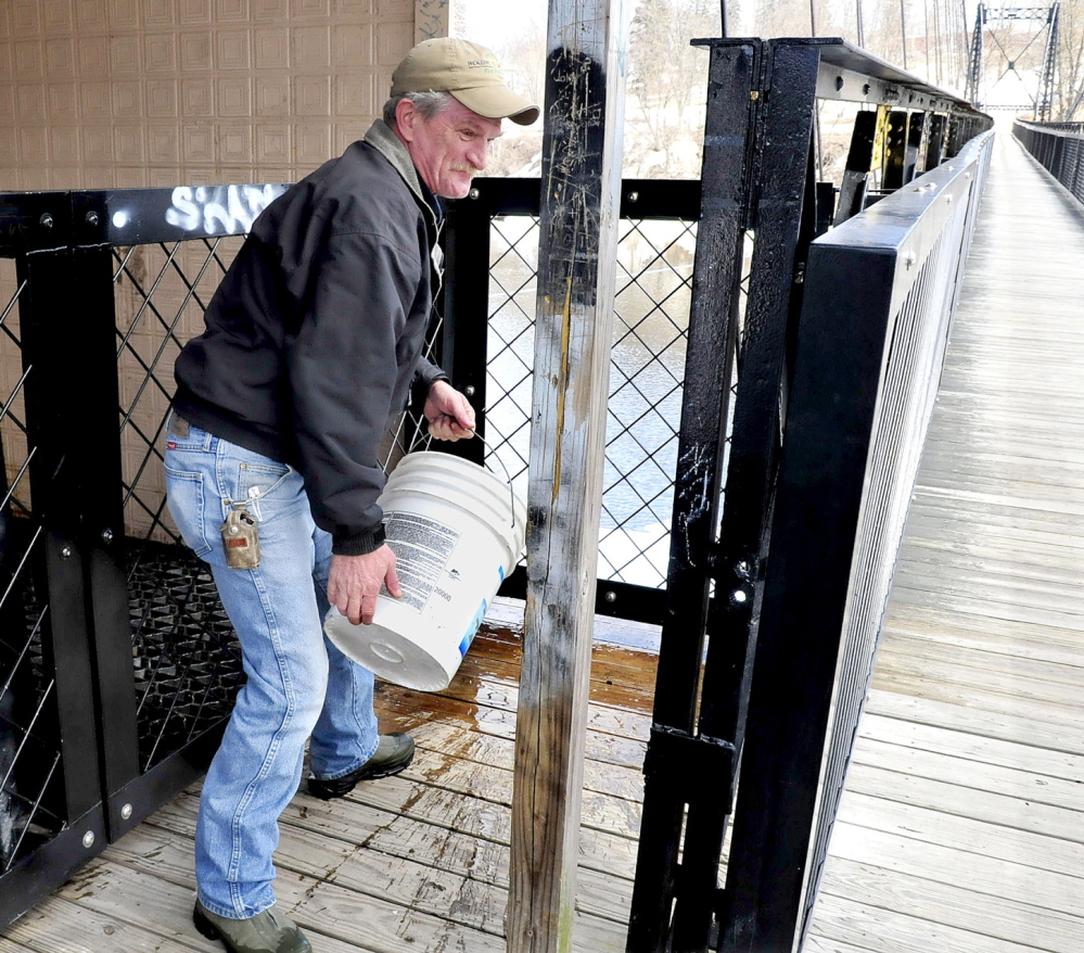 CLEAN UP: David Nevedomsky of Winlsow uses a bucket of water to wash off human excrement that was left on the Waterville side of the Two Cent bridge on Thursday.