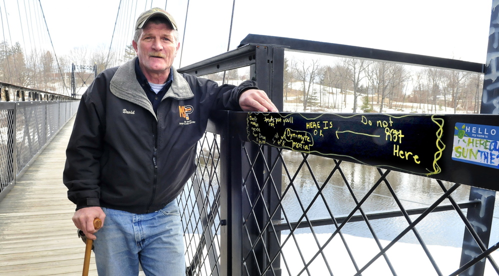 OFFENDED: David Nevedomsky, of Winslow, leans on a graffiti-covered railing on the Waterville side of the Two Cent Bridge on Thursday. Nevedomsky said he is offended by the vandalism on the historic footbridge, and Thursday cleaned human excrement off it after municipal officials didn’t respond to his complaints.