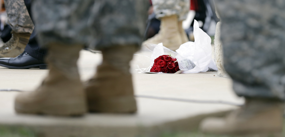 Roses left for shooting victims are seen at the feet of Lt. Gen. Mark Milley, U.S. Sen. John Cornyn, and other military during a news conference near Fort Hood’s main gate, Thursday, April 3, 2014, in Fort Hood, Texas. A soldier opened fire Wednesday on fellow service members at the Fort Hood military base, killing three people and wounding 16 before committing suicide.