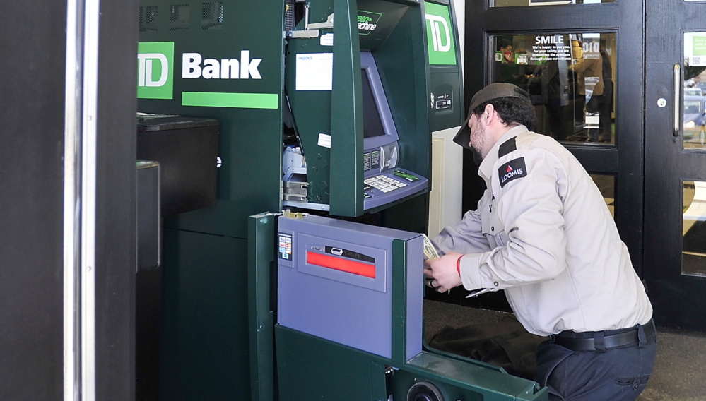 A guard from Loomis fills the ATM that a homeless man withdrew about $37,000 from Friday at the TD Bank on Maine Mall Road in South Portland.