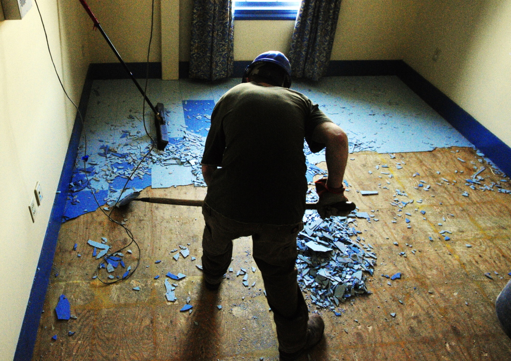 NEW TENANTS: MacKenzie Dunton, of Peachey Builders, chips tiles off the floor in the Haynes Building at the corner of St. Catherine and East Chestnut Streets, left, just up hill from the old MaineGeneral Medical Center on Friday in Augusta.