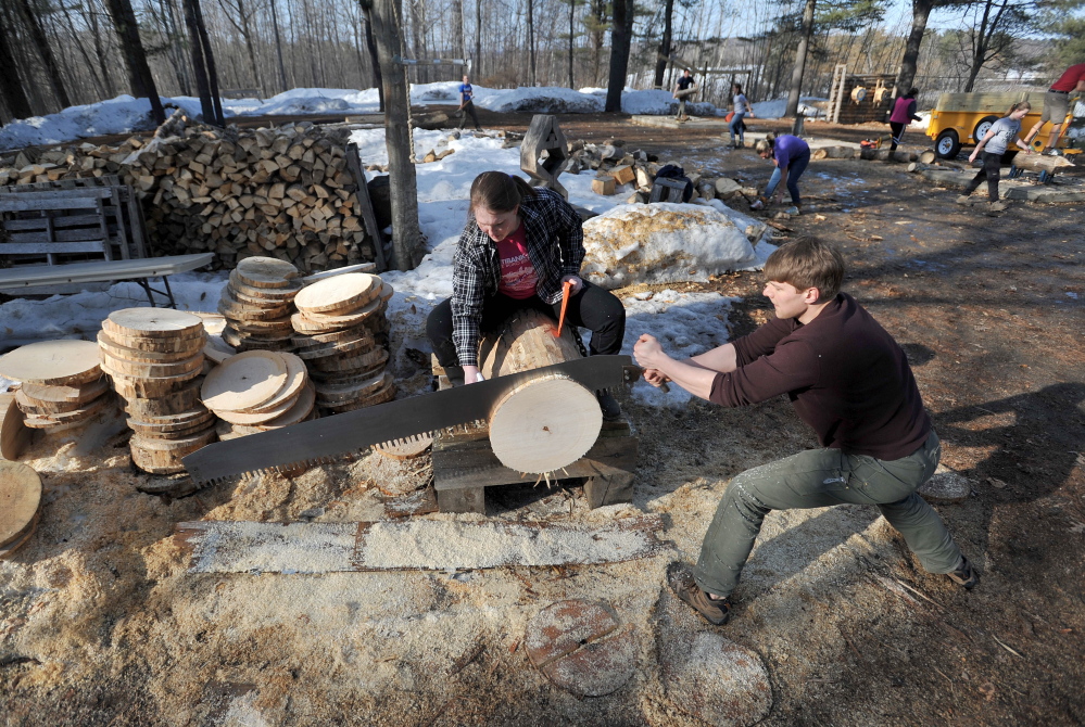 SAWING: Chris Krasniak, 20, works the buck saw as Tara Chizinski, 21, oils the saw and wedges the disc during timber sports practice at Colby College on Thursday.