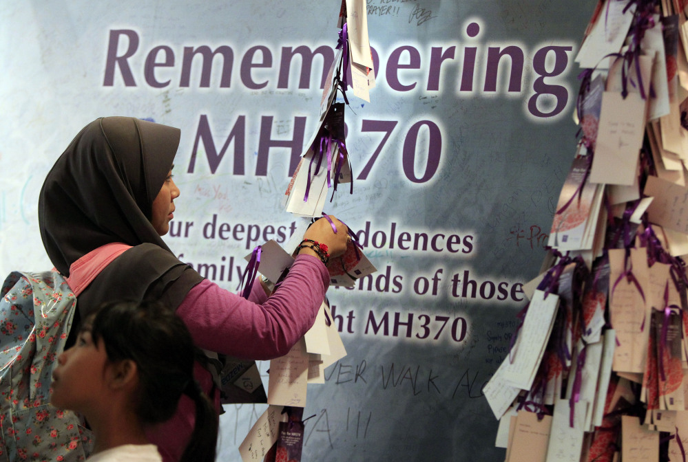 A woman ties a message for passengers aboard the missing Malaysia Airlines flight MH370, at a shopping mall in Kuala Lumpur, Malaysia, on Saturday. Search teams racing against time to find the flight recorders from the missing Malaysia Airlines jet crisscrossed another patch of the Indian Ocean on Saturday, four weeks to the day after the airliner vanished.