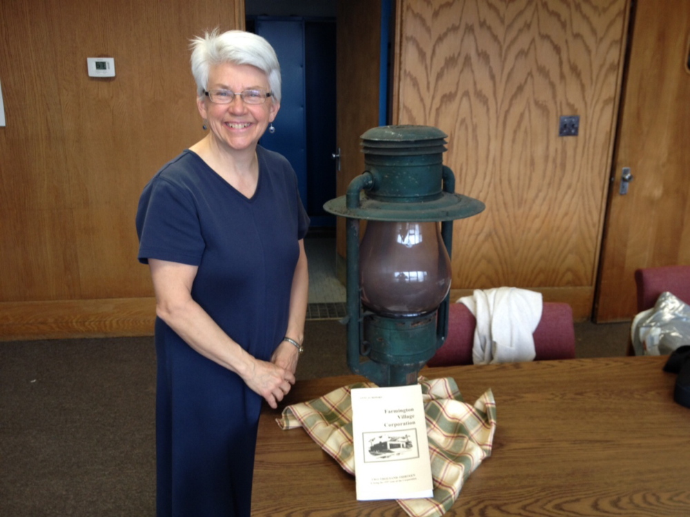LIGHT: Jane Woodman, business manager for the Farmington Village Corporation, stands next to a 130-year-old lamp that came from an era when the corporation, not the town, ran the municipal streetlights.