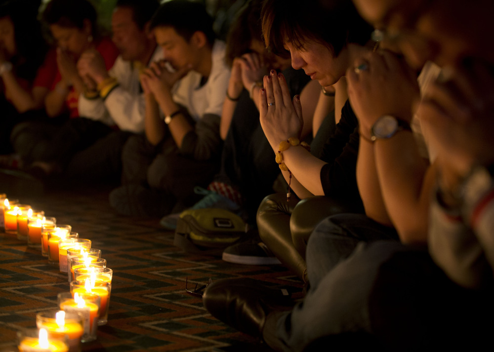 Relatives of Chinese passengers onboard Malaysia Airlines Flight 370 pray during a candlelight vigil for their loved ones at a hotel in Beijing, China on Tuesday, April 8.