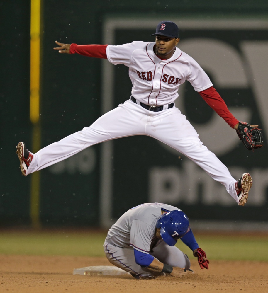 Boston Red Sox shortstop Xander Bogaerts, top, leaps over Texas Rangers left fielder Shin-Soo Choo as he turns a double play during the eighth inning of a MLB American League baseball game at Fenway Park, Monday, April 7, 2014, in Boston.