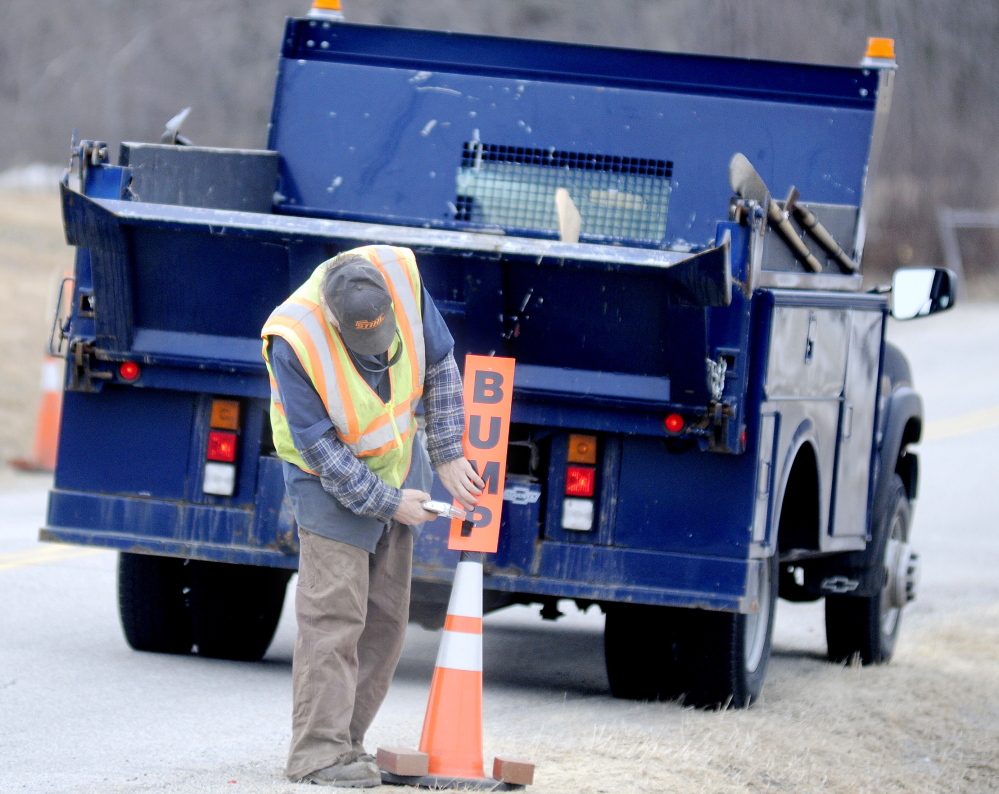 ROUGH RIDE: Hallowell Public Works employee Scott Haskell posts a sign in front of a frost heave Monday on Vaughan Road. Haskell said the city had filled many potholes Monday but heaves are persisting this spring.