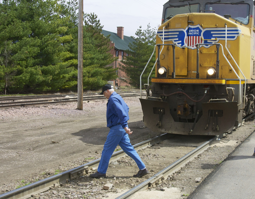 In this photo taken on April 7, 2010, a man crosses a railroad track in front of a stationary locomotive in Fremont, Neb. Regulators and the railroad industry are launching a new campaign Tuesday.