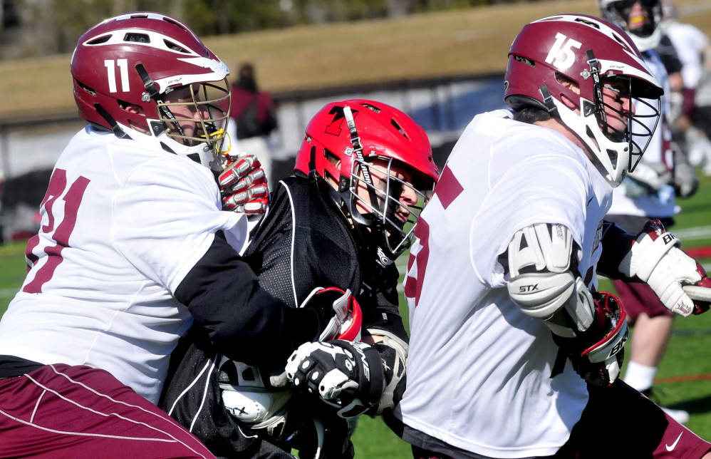 Staff photo by David Leaming Thomas College lacrosse player Parker Chute, center, is squeezed by University of Maine in Farmington players Jake Linkletter, left, and Connor Joy in Waterville on Wednesday, April 9, 2014.