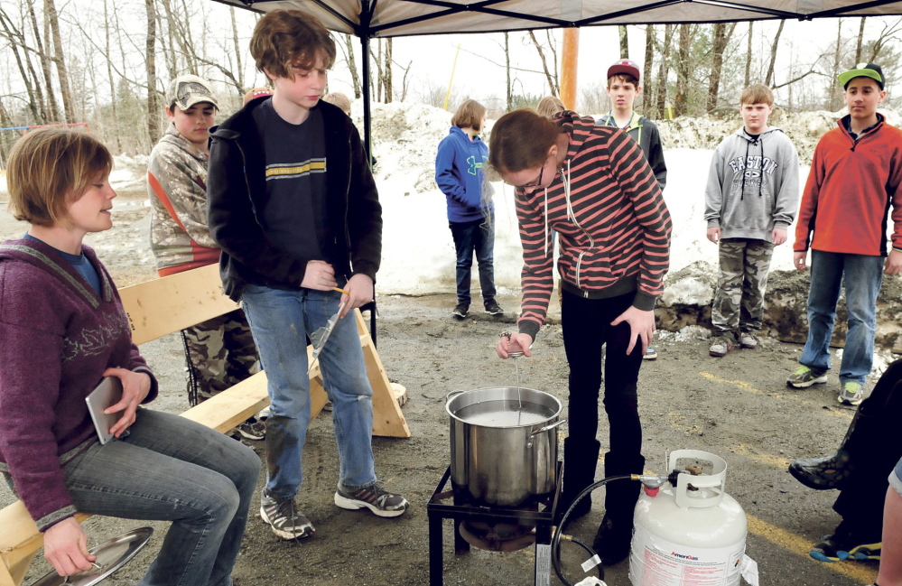 BOILING FAD: Cornville Regional Charter School student Grace Jewell takes a temperature reading of boiling maple sap Tuesday as Malcolm Harmon records the progress under direction of teacher Johanna Burdet, left.