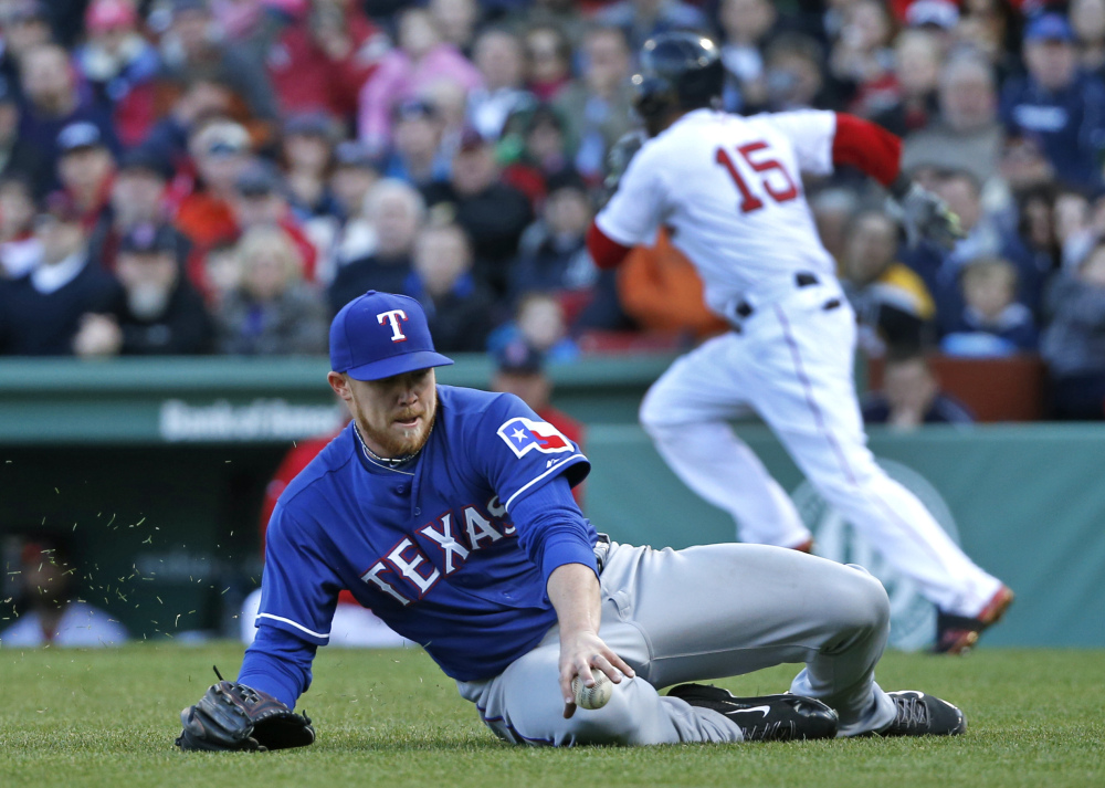 Texas Rangers starting pitcher Robbie Ross slides to field a ground ball single by Boston Red Sox’s Dustin Pedroia (15) in the third inning of a baseball game at Fenway Park in Boston, Wednesday, April 9, 2014.