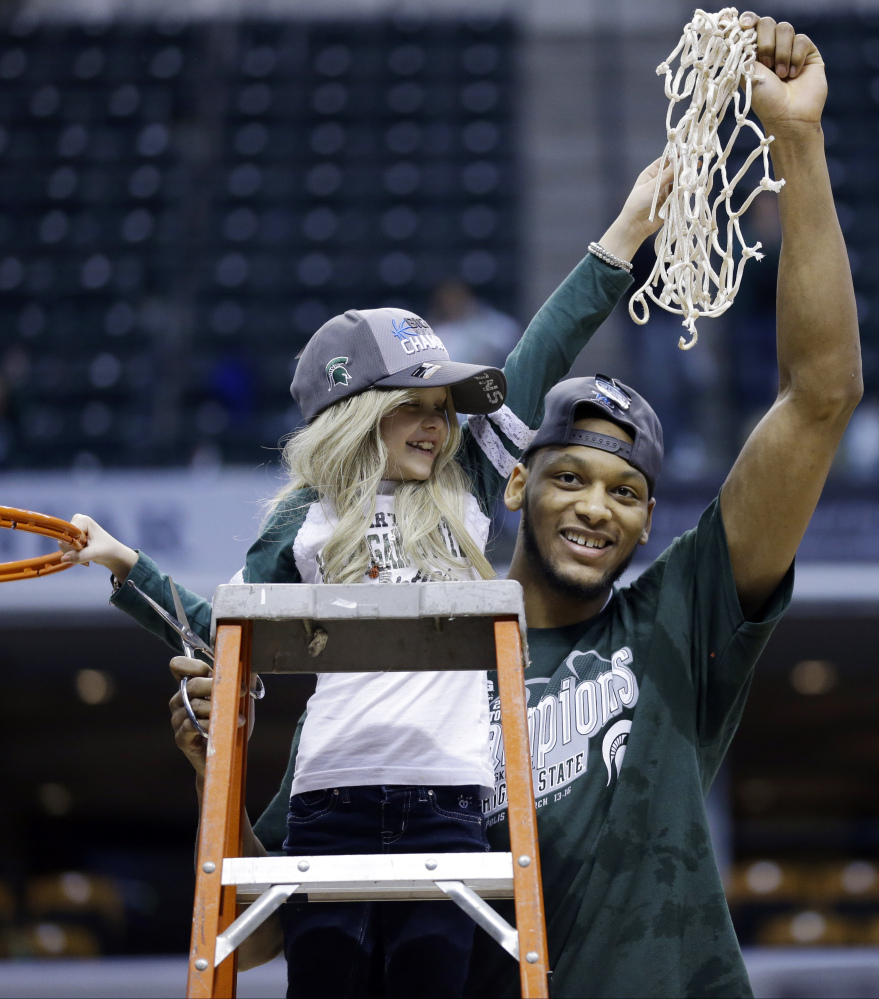 Michigan State forward Adreian Payne hoists the net with Lacey Holsworth after Michigan State defeated Michiganin an NCAA college basketball game.