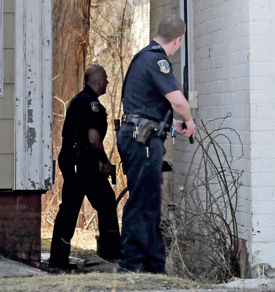CAUTION: Waterville police officers Tim Hinton, left, and Damon Lefferts wait with their firearms drawn while calling out for Peter Corson who later came out and was arrested at 12 Spring St. in Waterville on Thursday.