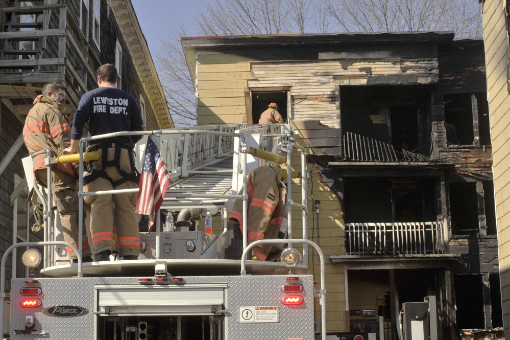 Lewiston firefighters work Thursday to clear the scene of an apartment building fire on Howe Street in Lewiston that left several dozen people homeless.