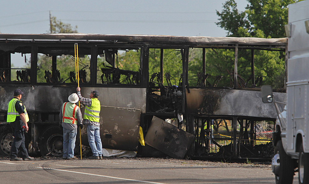 Investigators look over the charred remains of a tour bus Friday in Orland, Calif. At least 10 people were killed and dozens injured in the fiery crash on Interstate 5 .