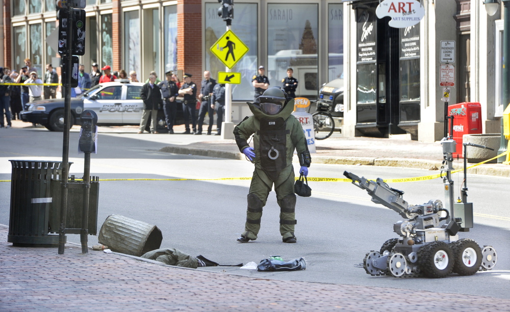 A Portland police bomb squad member and robot remove a device from a trash can Friday morning at the CVS drugstore at 510 Congress St. The device, used during a robbery, resembled a bomb but was found not to be explosive.