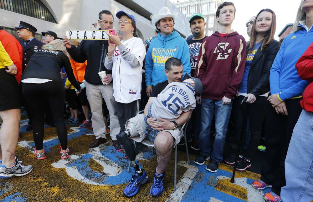 Boston Marathon bombing survivor Marc Fucarile, seated, talks to his son Gavin, 6, at the finish line of the Boston Marathon in Boston on Saturday. About 3,000 people, including survivors and first-responders showed up to participate in a Sports Illustrated photo shoot to commemorate the one-year anniversary of the bombings.