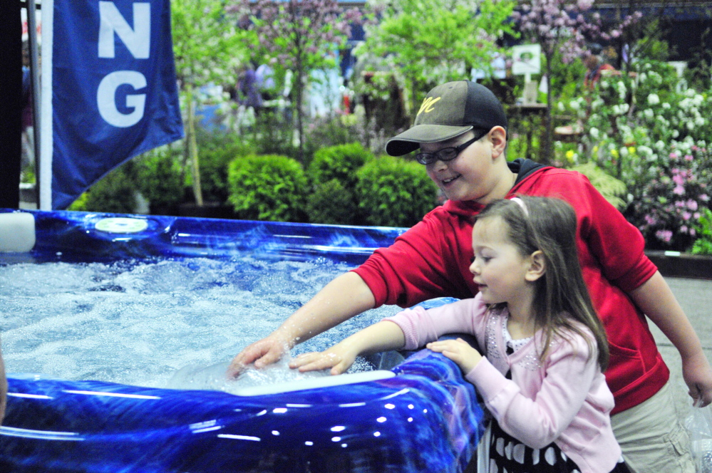 Just checking: Cooper Hall, top, and Olivia Hall test the warmth of water in a hot tub Saturday during the Manchester Lions Home and Garden Show at the Augusta Civic Center.