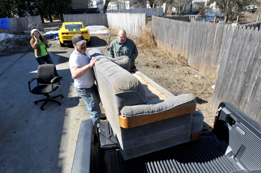 Sofa, so good: Chris Moody, 63, right, a volunteer with the South End Neighborhood Clean Up, gets help loading a couch into his truck Saturday from Chris Rancourt on Carey Lane in Waterville. The South End Clean Up, which happens once a year was created to help people who don’t have the capacity or ability to have large items moved to the dump or donated to charity.