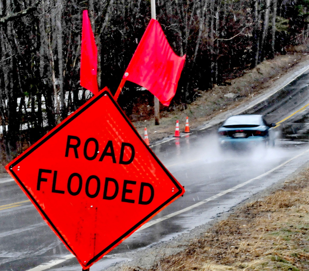SPRING RUNOFF: A motorist drives through water that collected on the Middle Road in Skowhegan just past warning signs on a wet Sunday. The National Weather Service has issued a flood watch for many parts of the state, including Kennebec, Somerset, Franklin and Waldo counties through Wednesday evening.