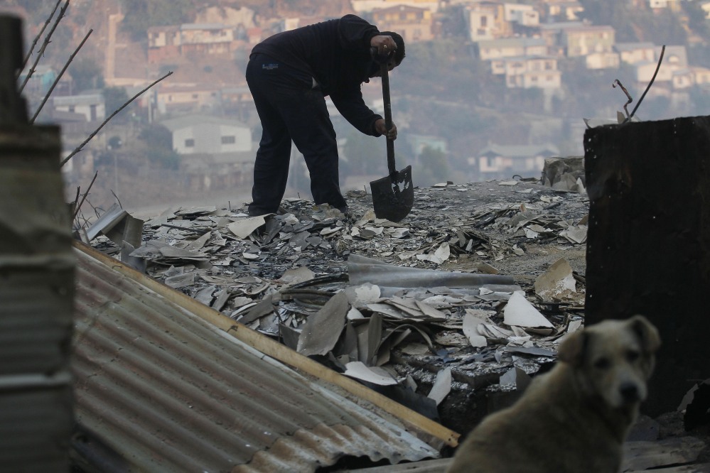 A man clears debris from his destroyed home after the forest fire reached urban areas in Valparaiso. The fires destroyed at least 2,000 houses by Sunday evening.