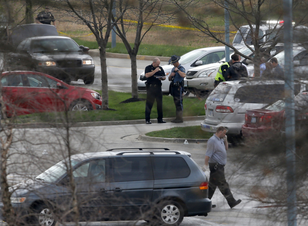 Investigators work behind a police line near the location of a shooting at the Jewish Community Center in Overland Park, Kan., Sunday.