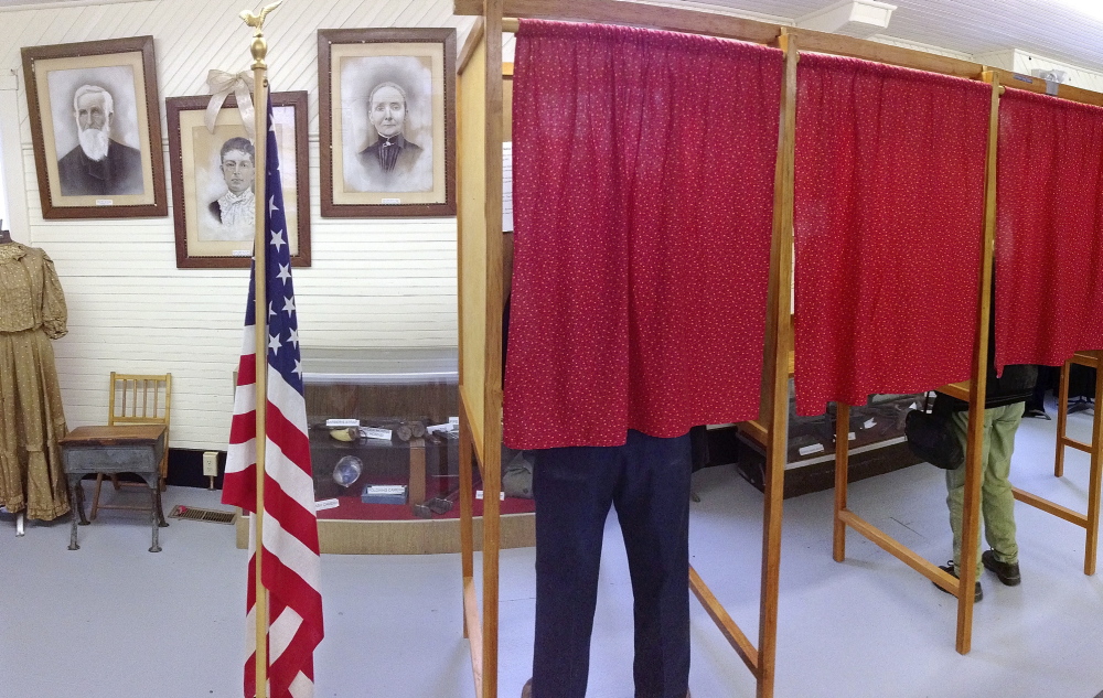 DECISION TIME: Voters cast ballots during a referendum Tuesday to decide whether the town will withdraw from Alternative Organizational Structure 97 at Starling Hall in Fayette. The building on Route 17 features displays set up by the Fayette Historical Society.