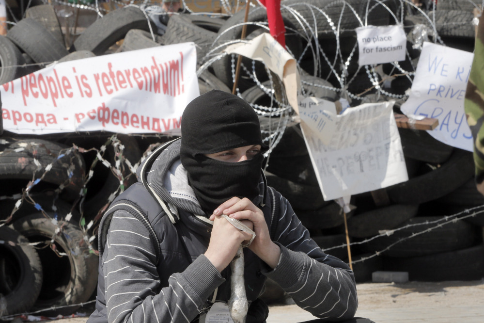 A masked pro-Russian activist guards a barricade at the regional administration building that they had seized earlier in Donetsk, Ukraine.