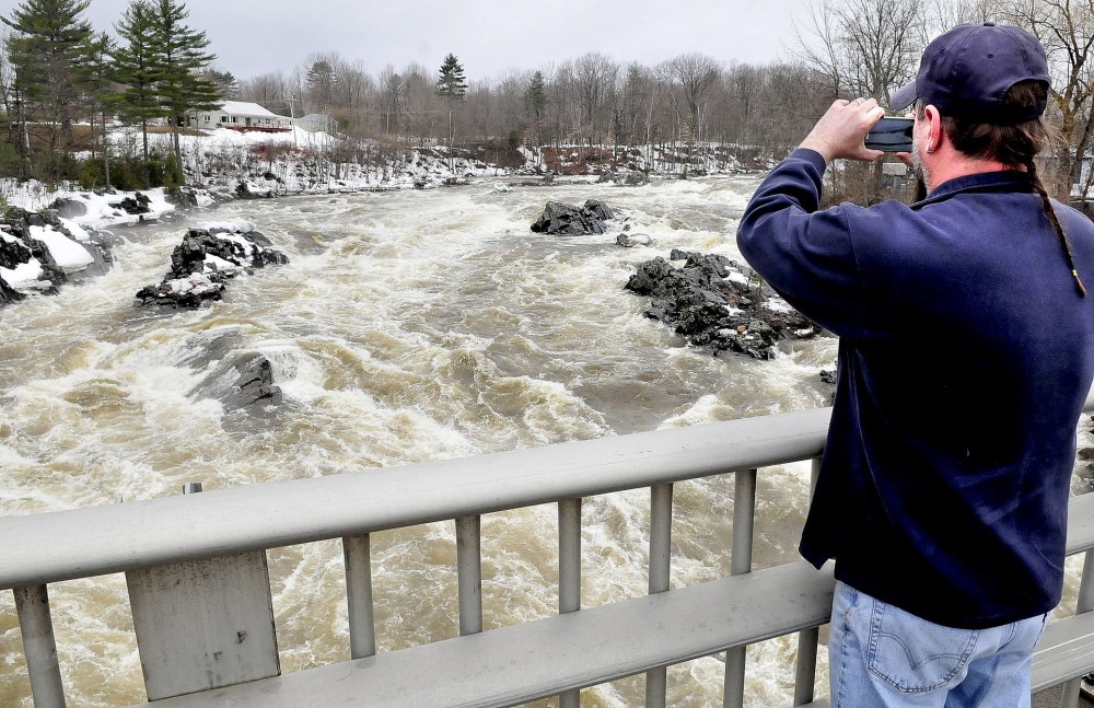 ON WATCH: Dana White,of New Portland, photographs the raging high water and ice chunks flowing down the Carrabassett River through North Anson on Tuesday.