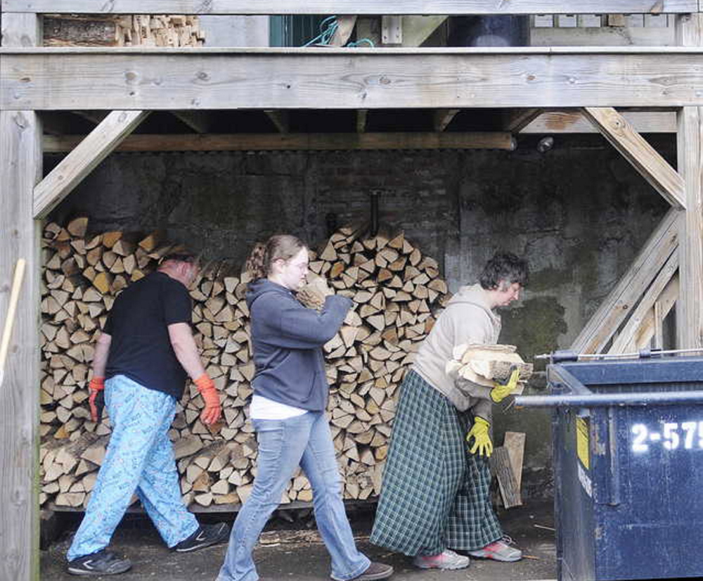 Staff photo by Andy Molloy GETTING READY: Donald Hallett, left, his daughter, Cassandra, and wife, Suzette, carry kiln dried firewood Tuesday up to the first floor deck of Kennebec Pizza with Christopher Stroot ahead of a flood expected to come up over the banks of the Kennebec River. Kennebec Pizza stores the firewood for its ovens beneath the building on the shores of the River. Officials expect the river to crest Wednesday on parking lots and roads adjoining the Kennebec.