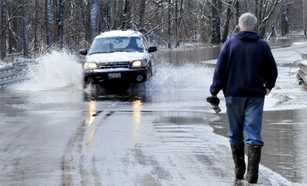 WET: Bob Hueston stops to photograph cars passing through the 6 inches of water that flowed over Prairie Road in Unity on Wednesday morning. High water from nearby Twenty-five Mile Stream flooded the road, but cars were able to get through.