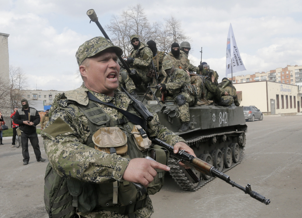 A pro-Russian gunman clears the way for a combat vehicle with gunmen on top in Slovyansk, Ukraine, Wednesday.