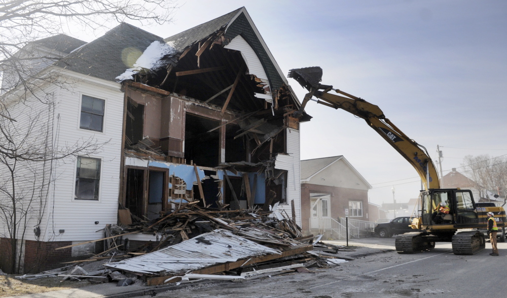 OUT WITH THE OLD: Scott McGee tears down the front of the Masonic Lodge in Winthrop on Thursday morning. McGee Construction razed the structure to make way for an expansion of C.M. Bailey Public Library.