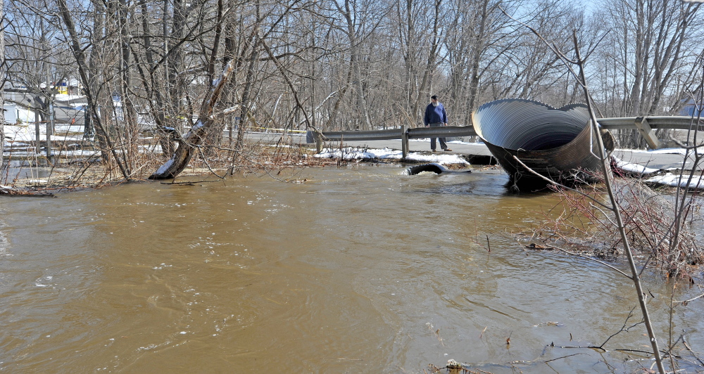 SWOLLEN STREAM: People stand on the road next to the swollen Sebasticook River East Branch on Wednesday as flooding closed Main Street in downtown Dexter.