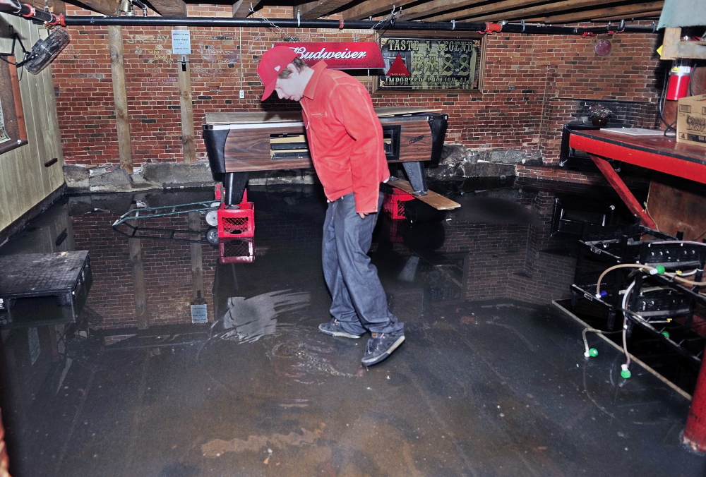 About an inch of water remains in the deepest spots where Brian Nichols inspects the back room of the Kennebec Wharf on Thursday in Hallowell.