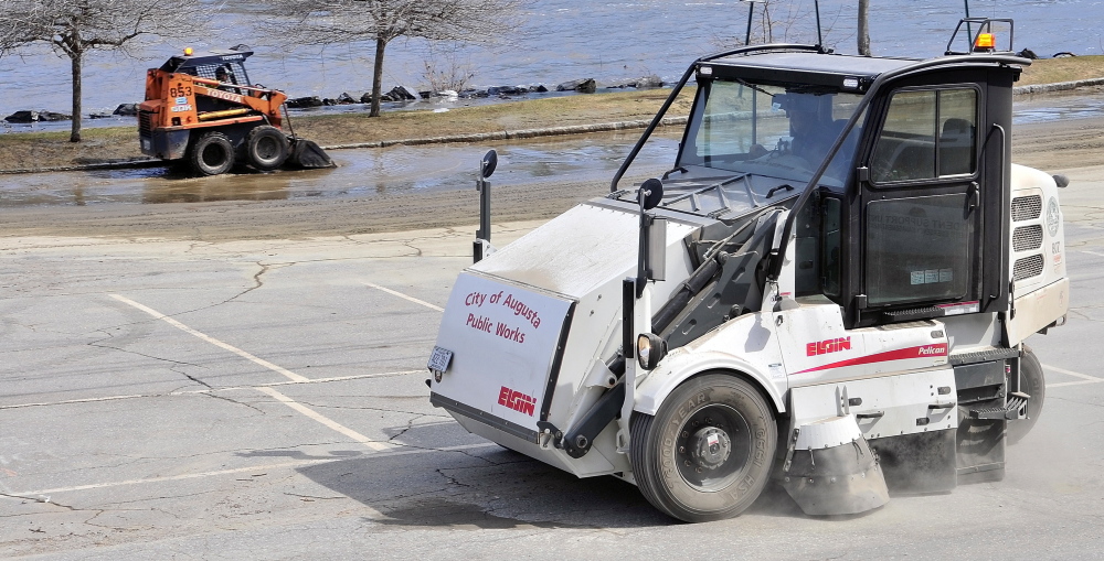City of Augusta workers clean up the Front Street parking lot Thursday in downtown Augusta. The river had receded from the lot behind the Olde Federal Building by Thursday afternoon, but there was still water in the parking lot to the north of there.