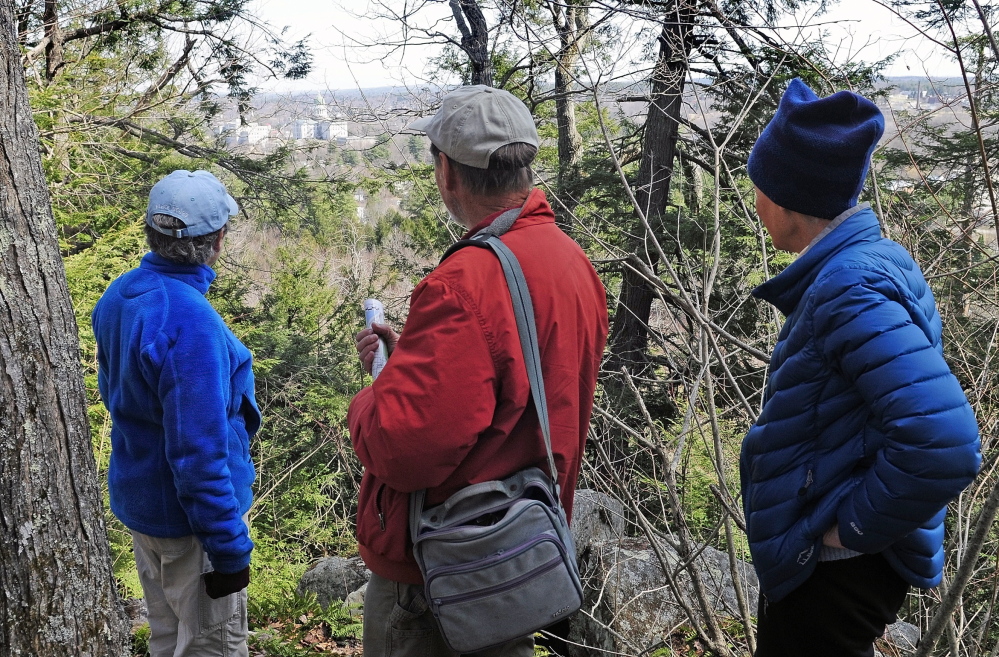 Hilltop view: City Councilor Dale McCormick, left, Brian Kent and Sue Bell look down from the summit onto the State House complex during a walking tour of Howard Hill on Friday in Augusta. The wooded hill is the backdrop to the State House.