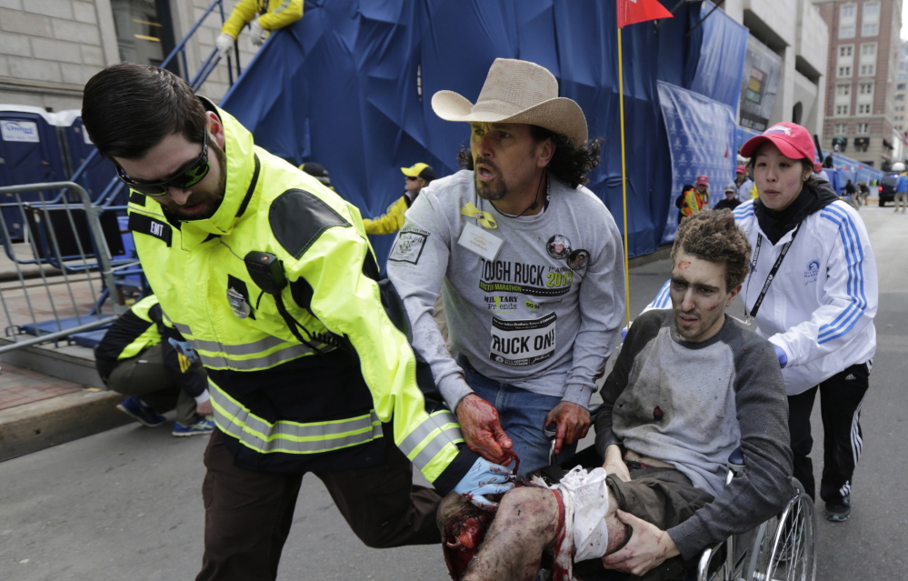 Carlos Arredondo, center, pushes Jeff Bauman in a wheelchair after Bauman was injured in the Boston Marathon bombings. Both Arredondo and his friend John Mixon of Ogunquit have been feted over the past year by Boston organizations grateful for their actions in the bombings’ aftermath.