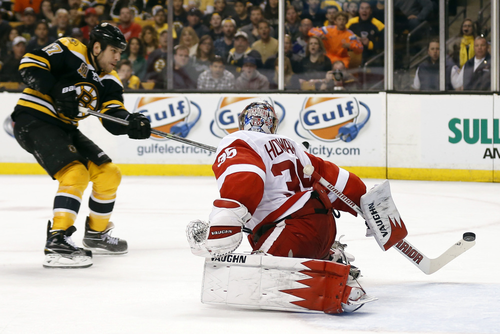 Boston Bruins’ Milan Lucic, left, scores on Detroit Red Wings goalie Jimmy Howard in the second period in Boston Sunday.