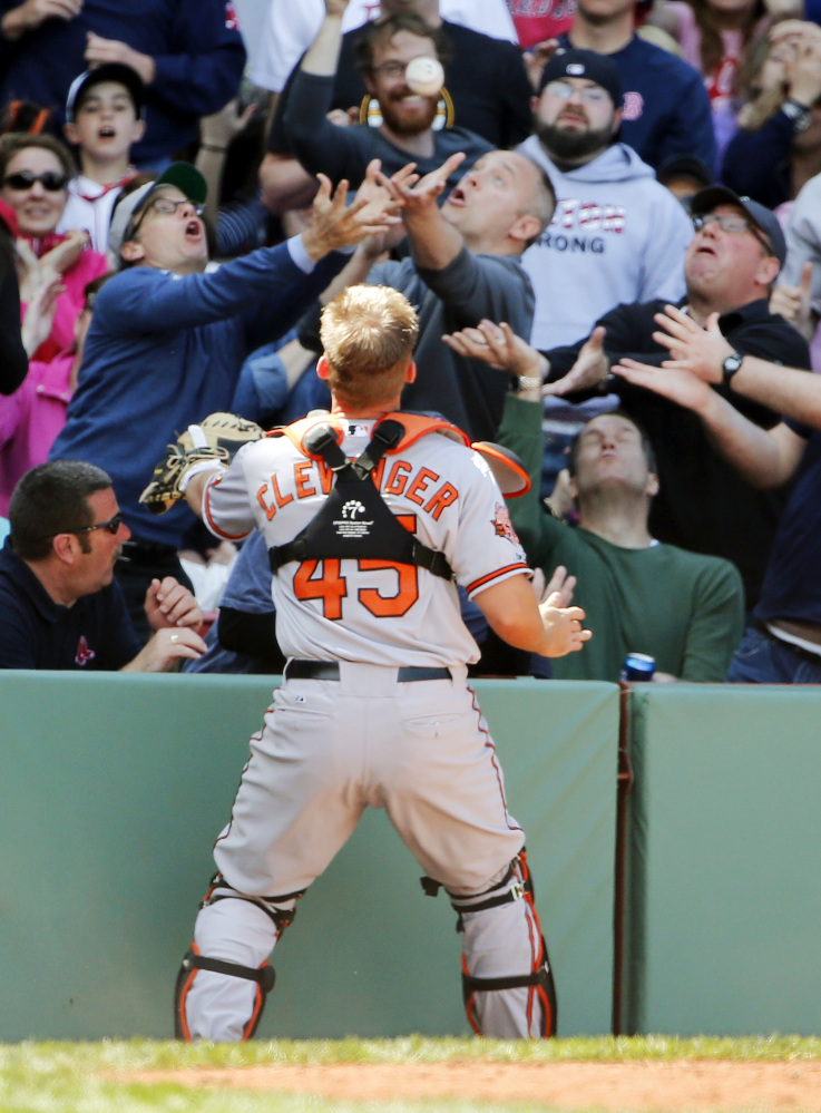 Baltimore Orioles catcher Steve Clevenger stands by as fans go for a foul popup by Red Sox Jackie Bradley Jr. during the ninth inning in Baltimore’s 7-6 win at Fenway on Monday.