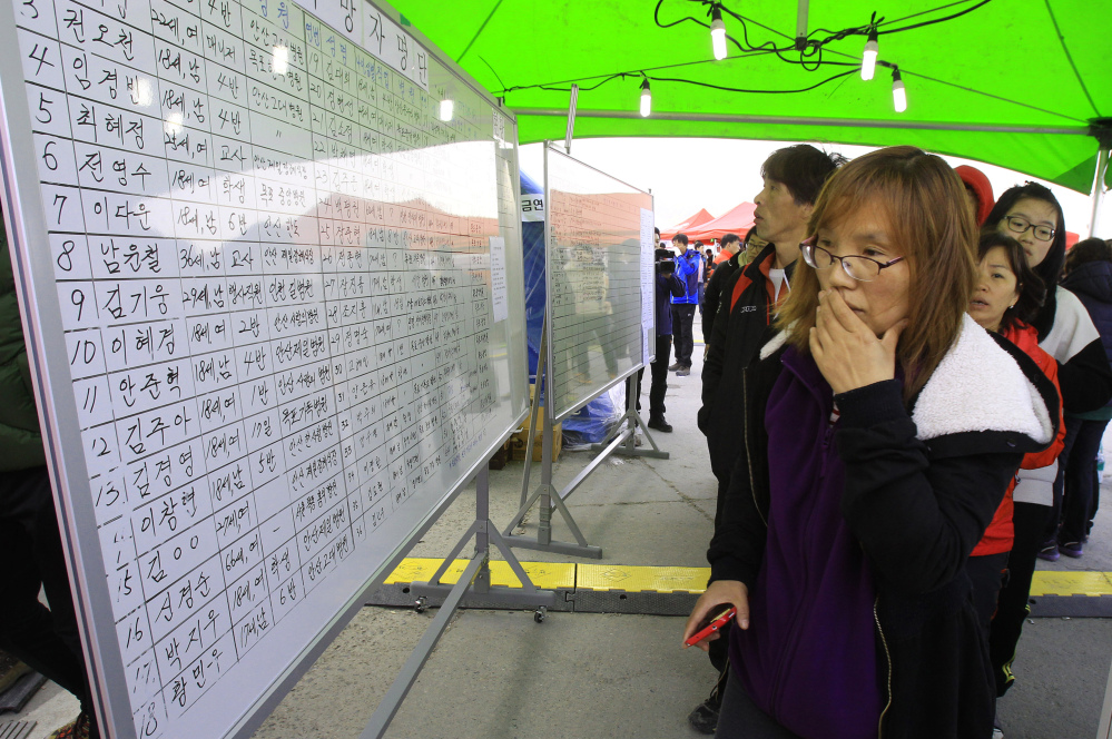 A relative of a passenger aboard the sunken ferry Sewol reads the official list of the dead, in Jindo, South Korea, on Monday. Anguish has turned to fury for some family members and people across the nation.