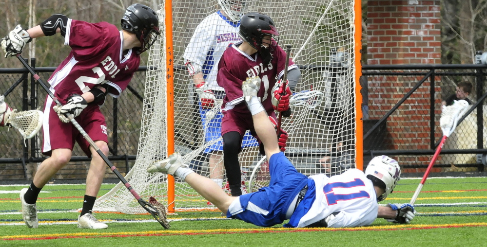 Staff photo by David Leaming Messalonskee's Josh Yonnelli falls in front of Edward Little's goalie Chris Poisson after scoring in Waterville on Tuesday, April 22, 2014.