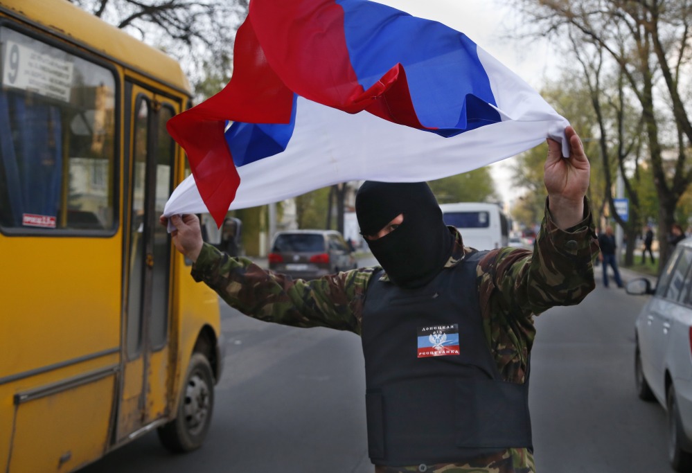 A masked pro-Russia demonstrator waves the Russian flag in Donetsk, eastern Ukraine, on Tuesday. U.S. Vice President Joe Biden warned Russia on Tuesday that “it’s time to stop talking and start acting” to reduce tension in Ukraine.