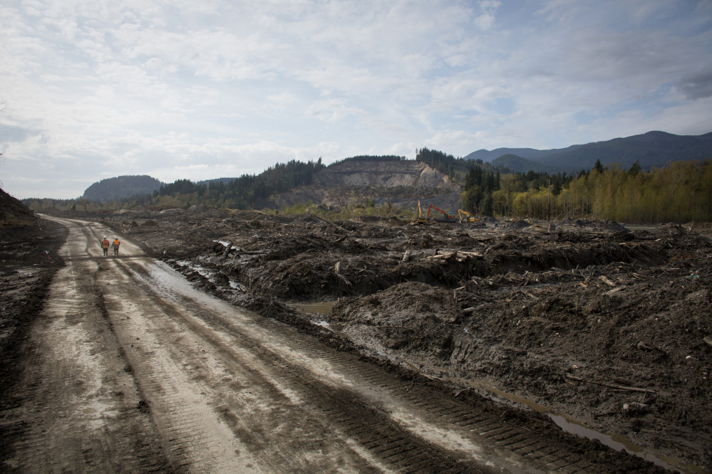 Washington Army National Guard soldiers walk along a road cut through the middle of the Oso mudslide on Monday.