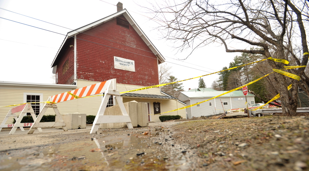 Staff photo by Michael G. Seaman LEFT HANGING: The Dexter Historical Society Grist Mill Museum remains in a precarious state Tuesday after flooding threatened the structure and washed out a road in Dexter last week.