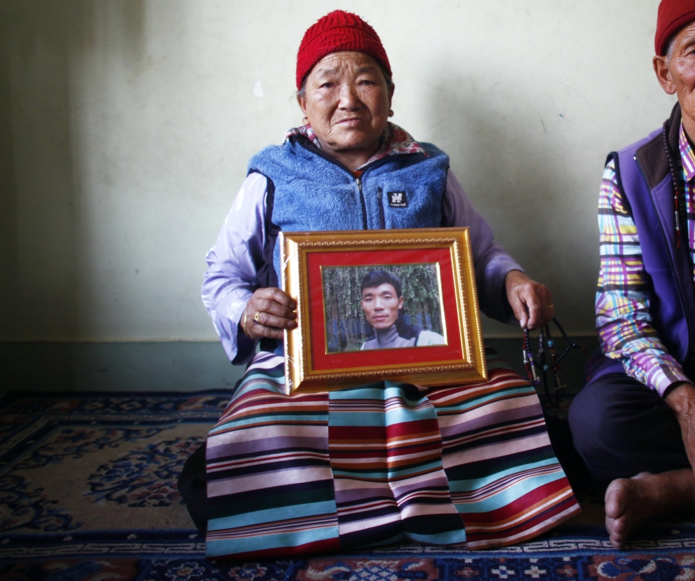 In Katmandu, Nepal, on Wednesday, Nimdige Sherpa holds a portrait of her son – avalanche victim Ang Kaji Sherpa – with her husband Ankchu Sherpa at her side.