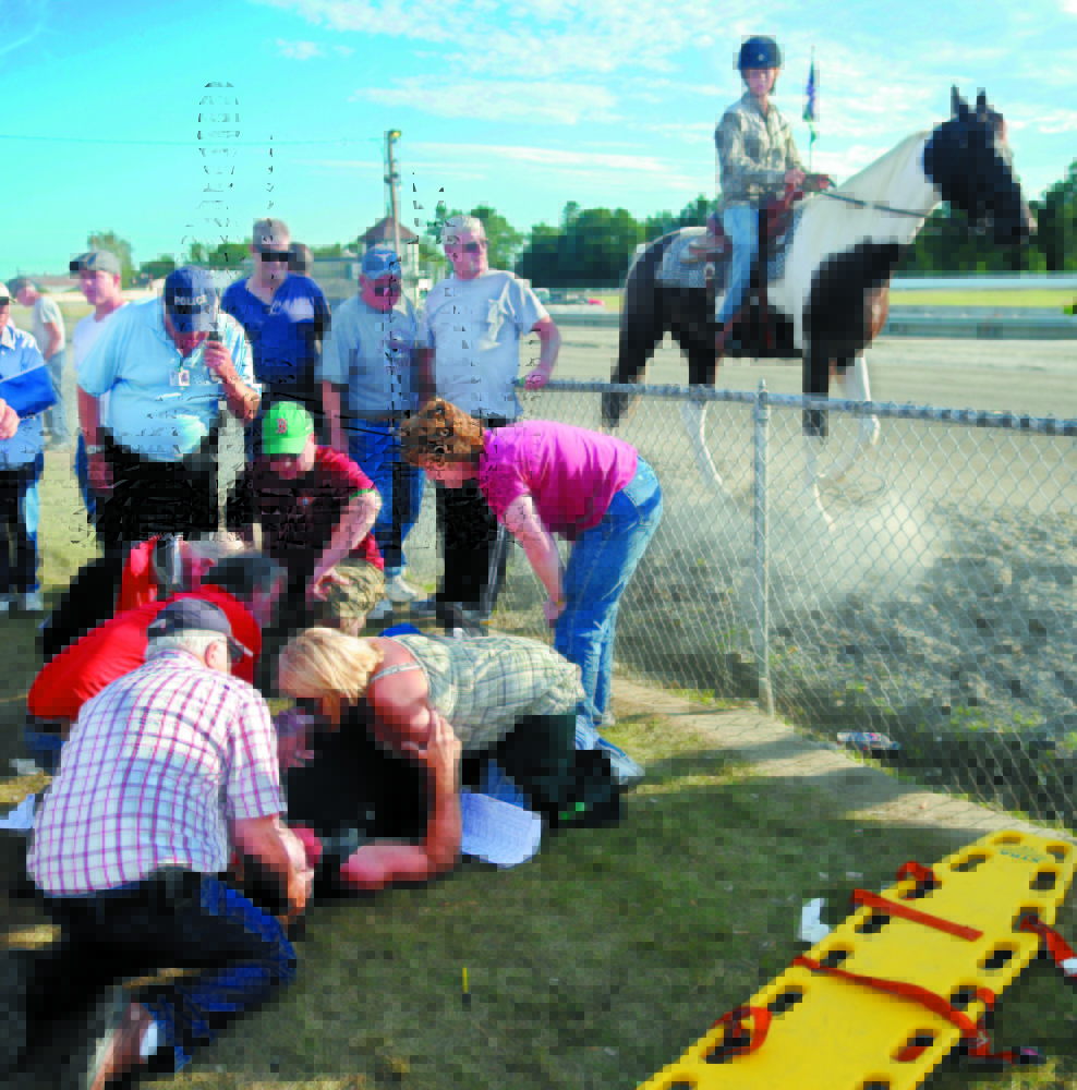 gate accident: People attend to the injured who were struck by the racing gate at the start of the 13th race at the WIndsor Fair in this September 2010 photo. The gate, towed by a vehicle, hit five people watching the race.