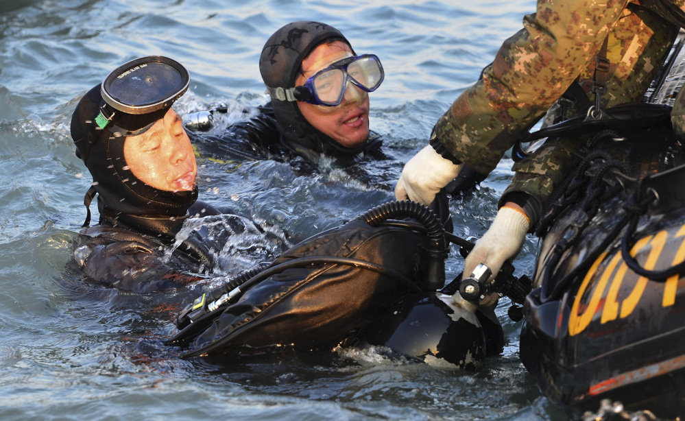 Divers look for people believed to have been trapped in the sunken ferry Sewol in the water off the southern coast near Jindo, South Korea. The grim work of recovering bodies from the ferry proceeded rapidly Wednesday, though a government official said divers must now rip through cabin walls to retrieve more victims.
